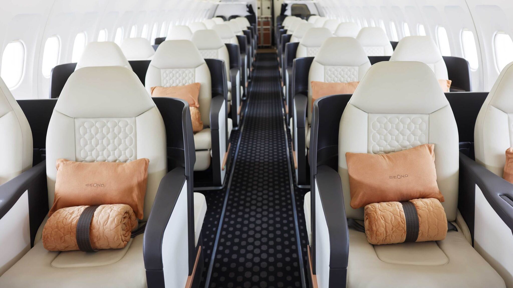 beOnd Airlines aircraft cabin with cream leather seats and orange cushions