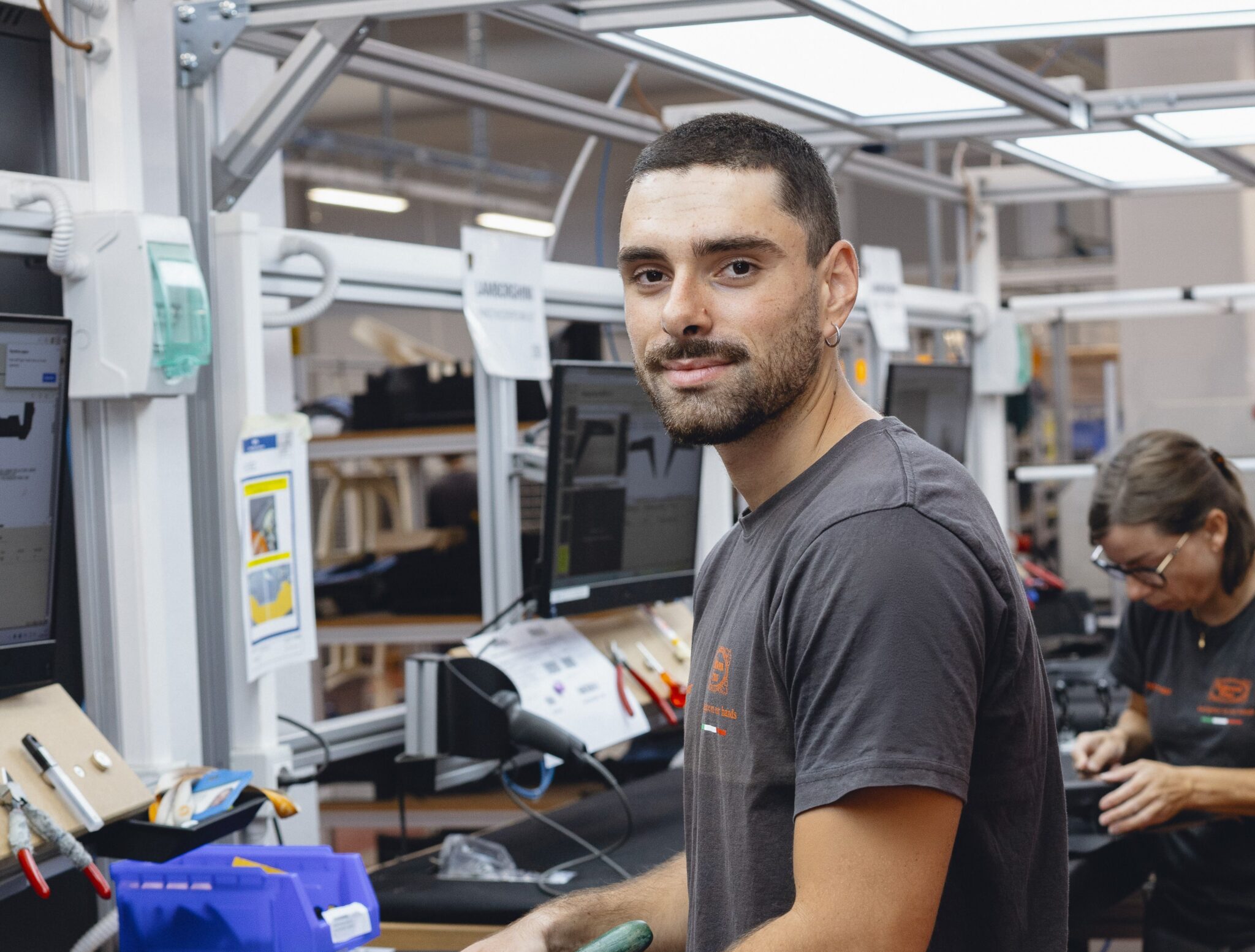 Giovane operaio in un reparto di produzione che guarda verso la fotocamera