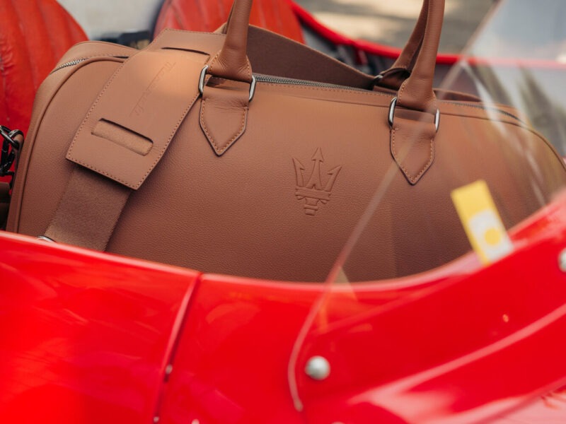 Detail of the Maserati weekend bag in Pelle Frau® leather with the Trident logo on a red Maserati