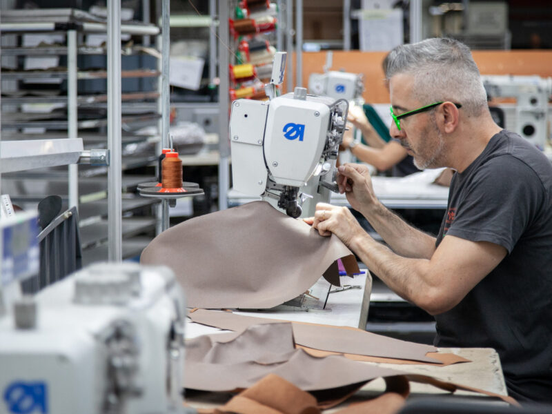 Artigiano al lavoro su una macchina da cucire industriale per la lavorazione della pelle