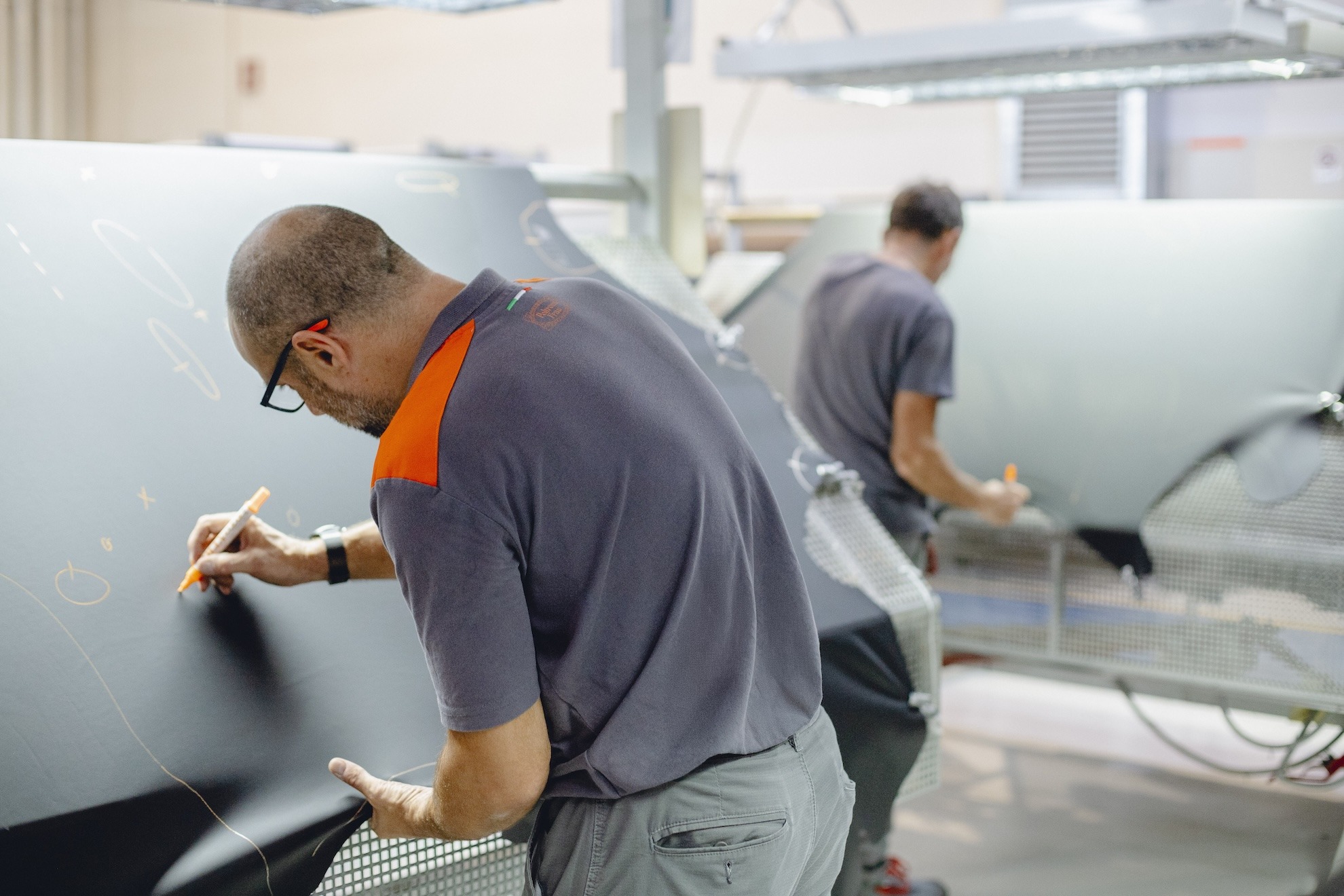 Craftsmen marking a leather panel by hand before cutting