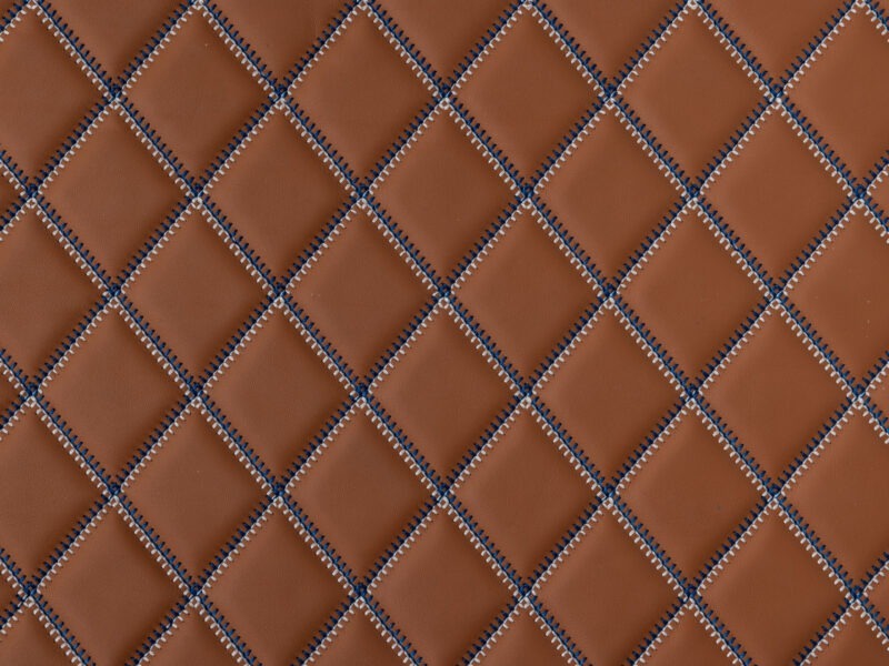 Detail of rust leather with diamond quilting and blue contrast stitching