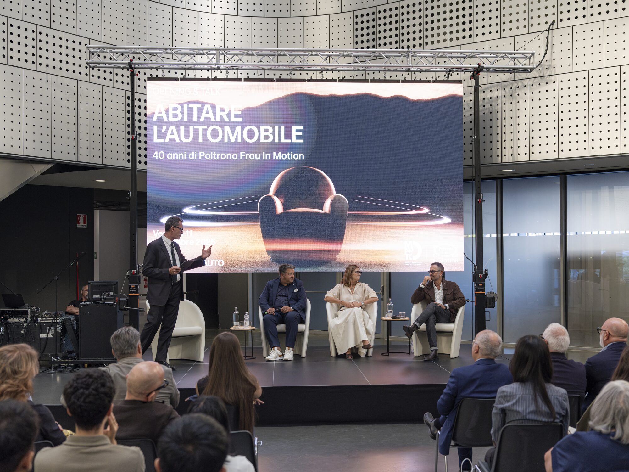 Presentation of the 'Living in Motion' event celebrating 40 years of Poltrona Frau In Motion, with a speaker and panel of guests on stage